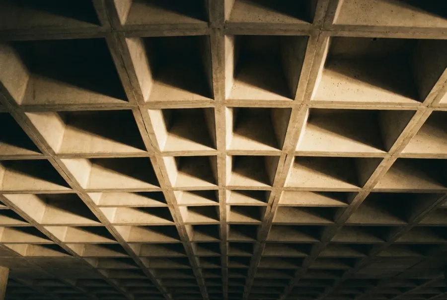 Detail of a modular concrete structure seen from below in raking light.